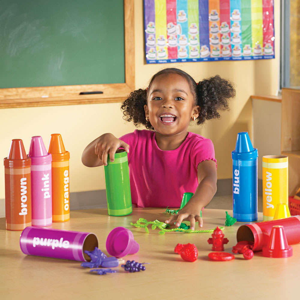 Preschool children sorting objects into rainbow crayon tubes
